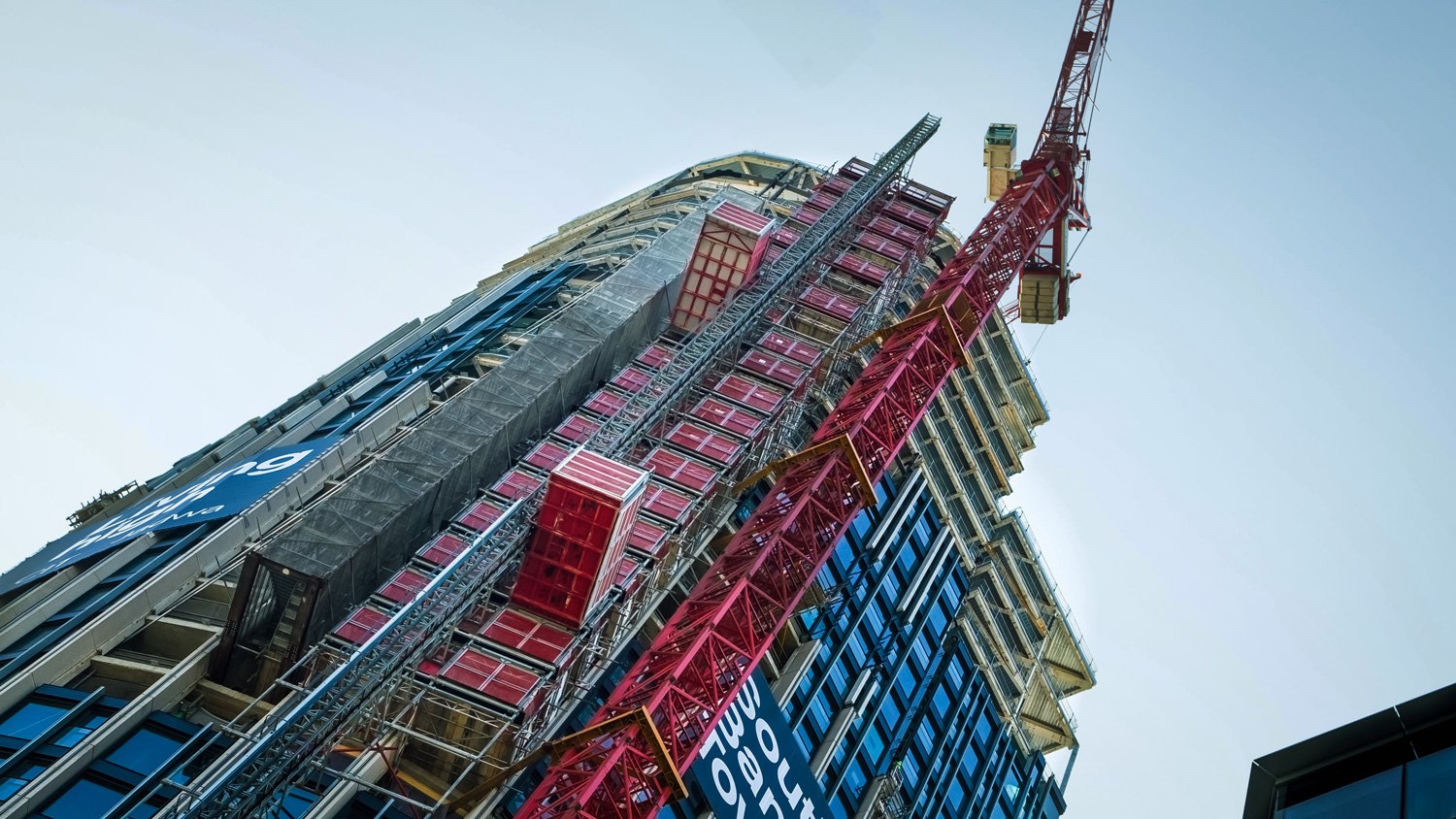 High-rise construction site with Alimak passenger goods hoist and tower crane