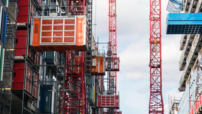 Multiple Alimak construction hoists at buidling site with towercranes