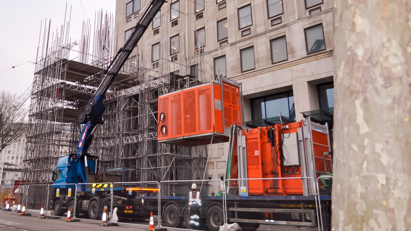 A mobile crane installing two Alimak Construction Hoists